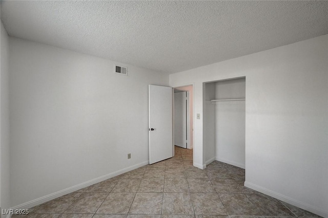 unfurnished bedroom with visible vents, a textured ceiling, a closet, light tile patterned floors, and baseboards