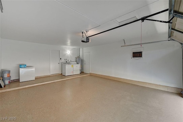 garage featuring refrigerator, a garage door opener, water heater, and washing machine and clothes dryer