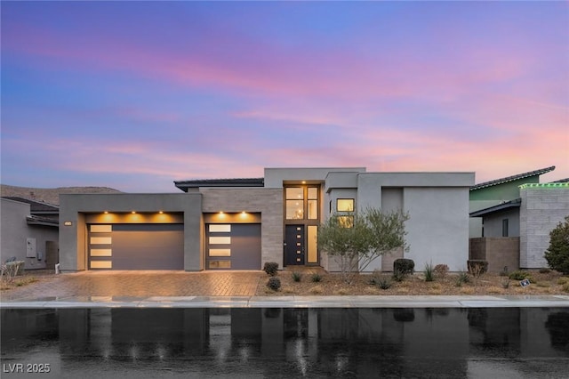 contemporary house featuring decorative driveway, a garage, and stucco siding