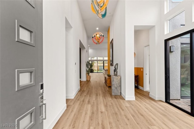 foyer featuring a high ceiling, light wood-style flooring, recessed lighting, and baseboards