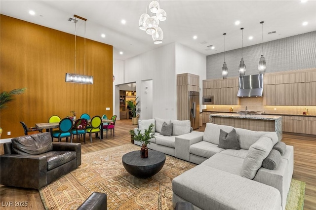 living room featuring recessed lighting, light wood-style floors, and a towering ceiling