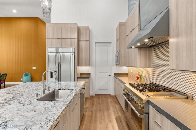 kitchen with ventilation hood, light brown cabinets, a sink, modern cabinets, and premium appliances