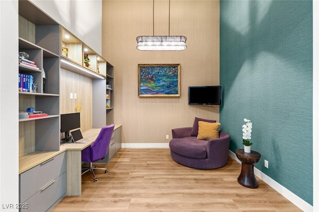 office area featuring baseboards, light wood-style floors, and built in desk