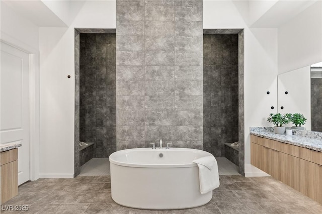 full bath featuring tile patterned floors, a freestanding bath, tile walls, and vanity