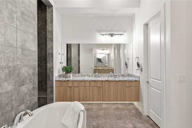 bathroom with double vanity, a freestanding tub, and a sink