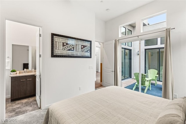 bedroom with access to exterior, light colored carpet, a towering ceiling, and connected bathroom