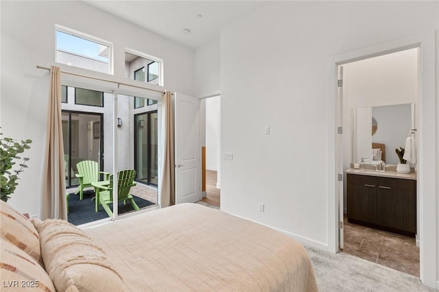 bedroom with light carpet, ensuite bathroom, a sink, a towering ceiling, and access to exterior