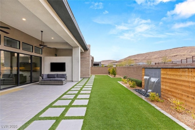 view of yard with outdoor lounge area, a patio, a ceiling fan, and a fenced backyard