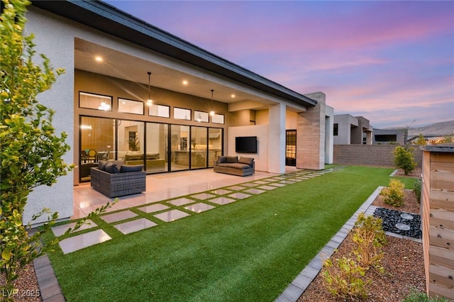 back of house featuring an outdoor living space, fence, stucco siding, a lawn, and a patio