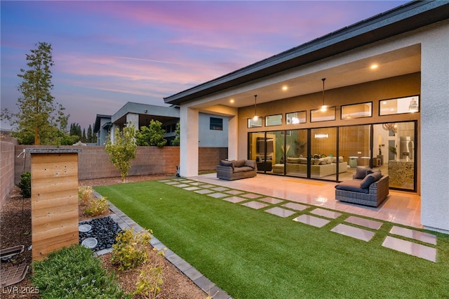 back of house featuring stucco siding, a lawn, a patio, a fenced backyard, and outdoor lounge area