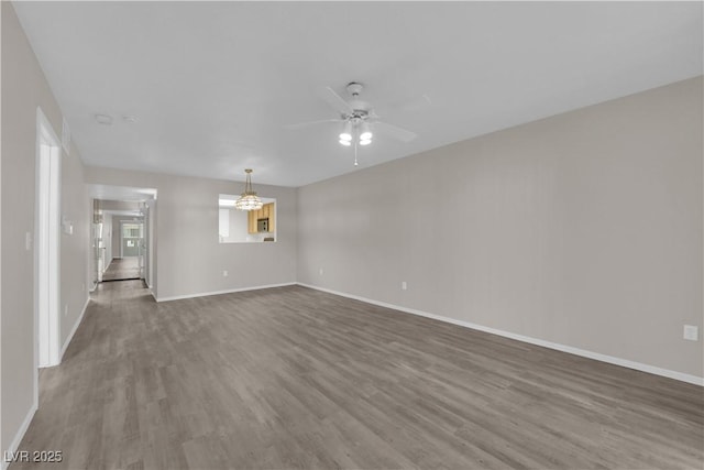 unfurnished living room with a ceiling fan, wood finished floors, and baseboards