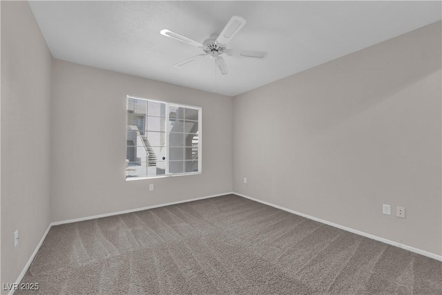 carpeted spare room featuring baseboards and ceiling fan