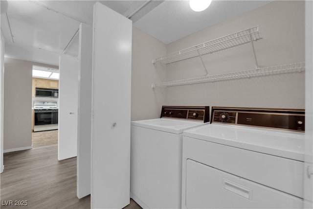 laundry area with laundry area, light wood-style floors, and washing machine and clothes dryer