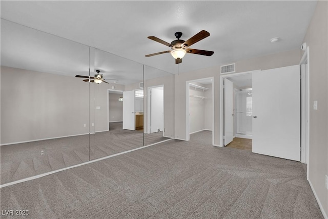 unfurnished bedroom featuring a spacious closet, visible vents, ceiling fan, carpet floors, and ensuite bathroom