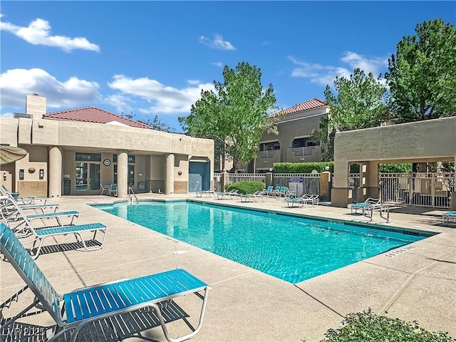 community pool with a patio and fence