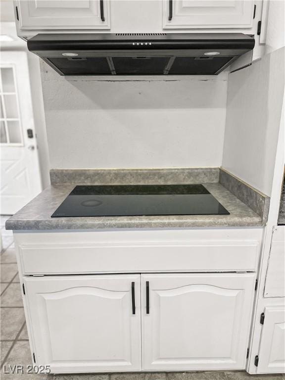 interior space featuring light tile patterned floors, white cabinetry, ventilation hood, and black electric cooktop