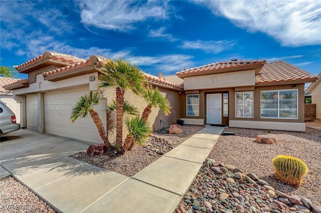 mediterranean / spanish-style home with stucco siding, driveway, an attached garage, and a tile roof