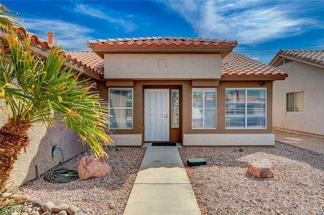 doorway to property featuring a tiled roof and stucco siding