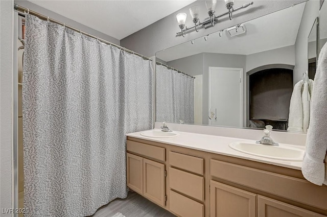 full bathroom with double vanity, wood finished floors, and a sink