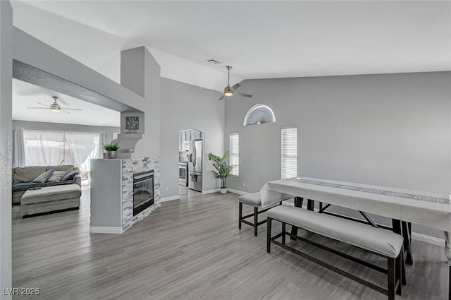 interior space featuring baseboards, wood finished floors, a glass covered fireplace, and a ceiling fan