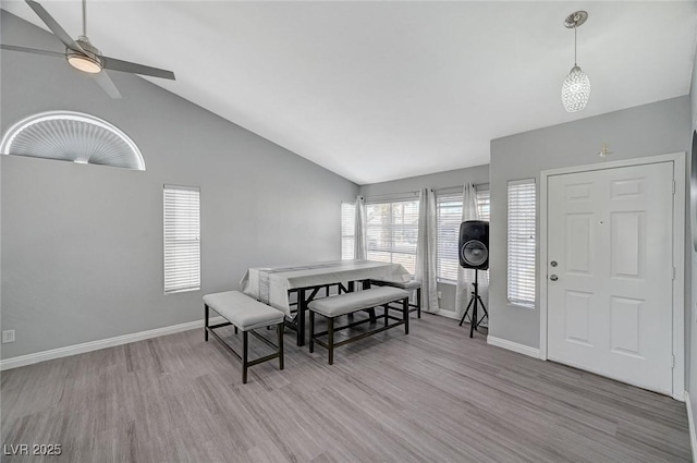 dining room with ceiling fan, high vaulted ceiling, baseboards, and wood finished floors