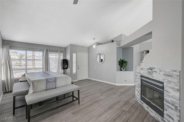 interior space with vaulted ceiling, a fireplace, baseboards, and wood finished floors