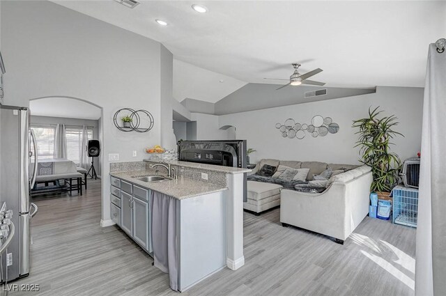 kitchen featuring a sink, light wood-type flooring, arched walkways, and freestanding refrigerator