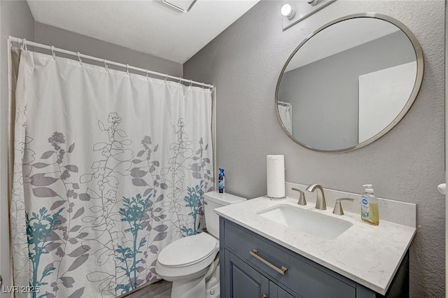 full bath featuring toilet, wood finished floors, vanity, and a textured wall