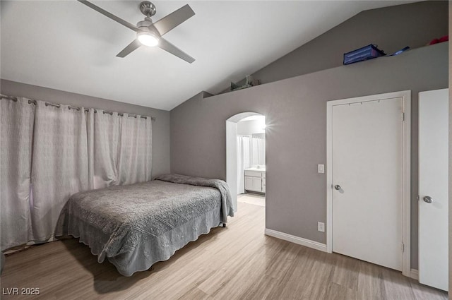 bedroom with a ceiling fan, wood finished floors, lofted ceiling, arched walkways, and connected bathroom