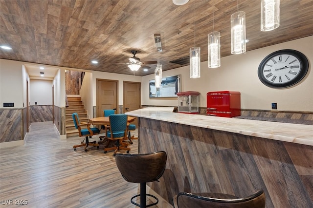 bar featuring wood finished floors, a bar, stairs, wooden ceiling, and decorative light fixtures