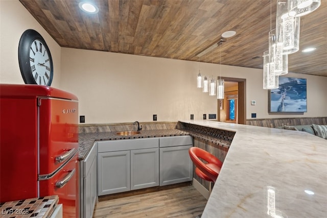 kitchen featuring light wood-style flooring, refrigerator, recessed lighting, a sink, and wood ceiling