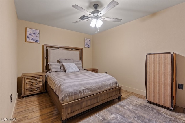 bedroom featuring ceiling fan, baseboards, and wood finished floors