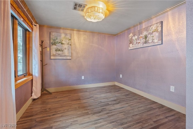 unfurnished room with visible vents, ornamental molding, baseboards, and wood finished floors