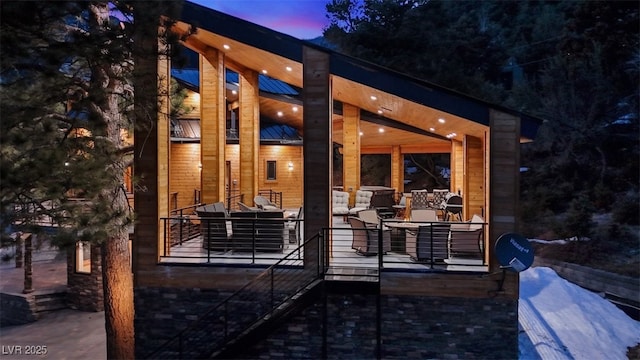 back of house at dusk featuring stairway and a patio area