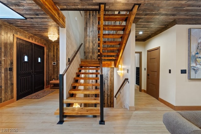 stairs with baseboards, wooden walls, and wood finished floors