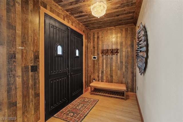 foyer entrance with wood finished floors, wood ceiling, baseboards, and wood walls