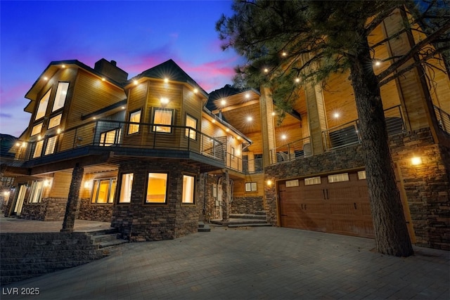 view of front of home with a balcony, decorative driveway, and an attached garage