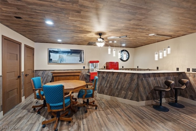 interior space with a wainscoted wall, recessed lighting, wet bar, and wood finished floors