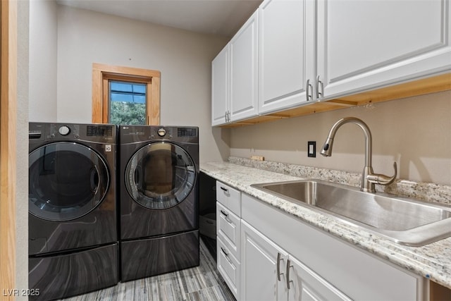 clothes washing area with cabinet space, independent washer and dryer, and a sink