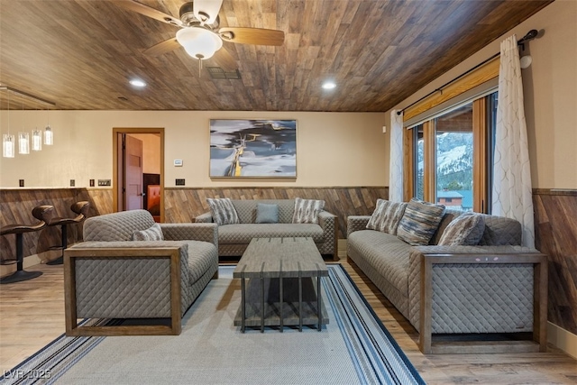 living area featuring a wainscoted wall, wood walls, and wooden ceiling