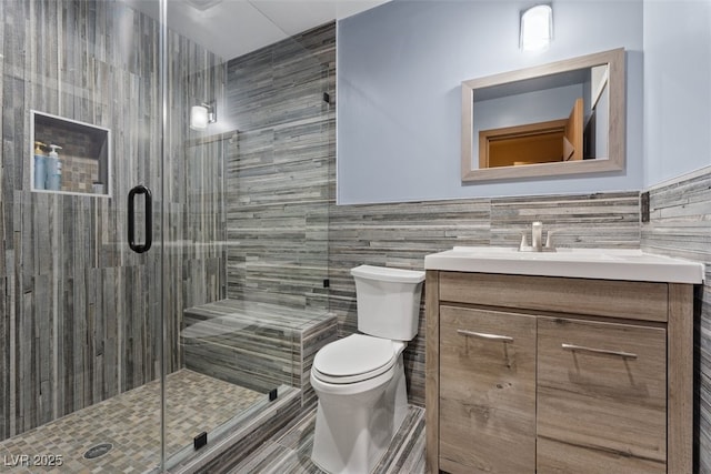 full bathroom featuring vanity, a shower stall, wainscoting, tile walls, and toilet