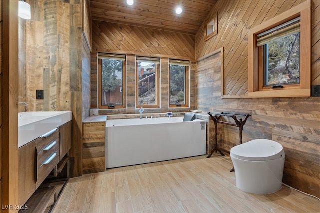 bathroom featuring a freestanding tub, toilet, wood finished floors, wood walls, and wood ceiling