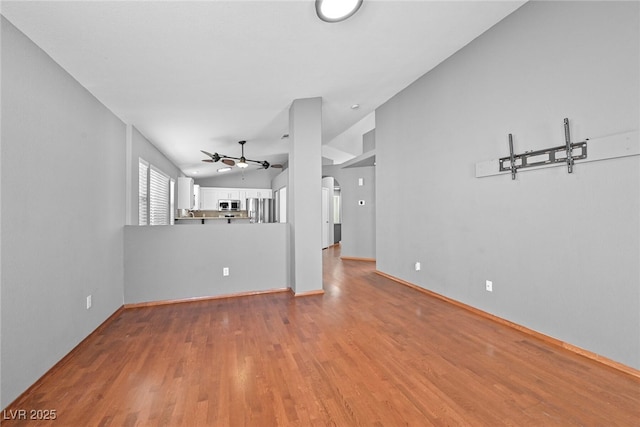 unfurnished living room with arched walkways, a ceiling fan, lofted ceiling, and wood finished floors