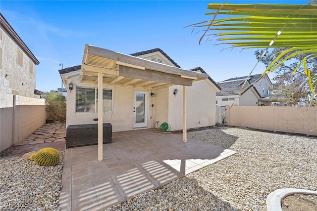 back of property with a patio area, stucco siding, and a fenced backyard