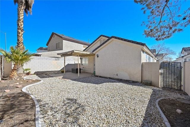 rear view of property with a patio, a gate, fence, stucco siding, and a tile roof