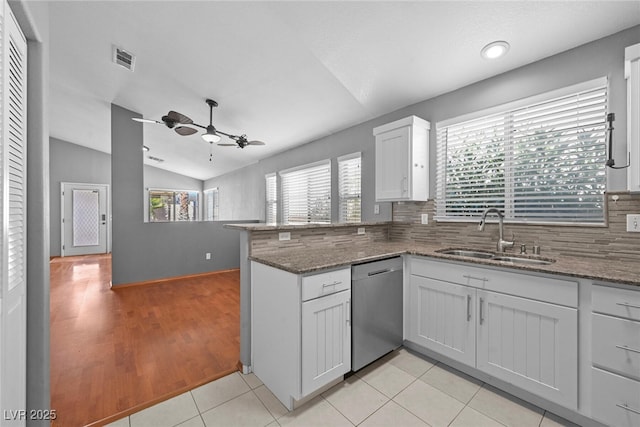 kitchen featuring visible vents, a peninsula, lofted ceiling, a sink, and dishwasher