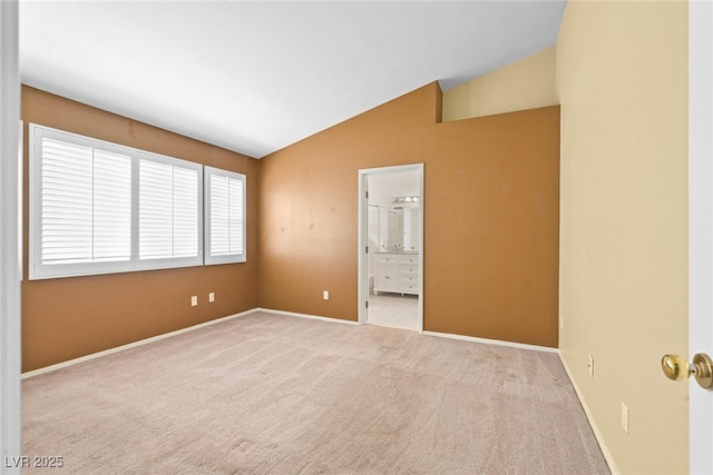 carpeted empty room featuring baseboards and lofted ceiling