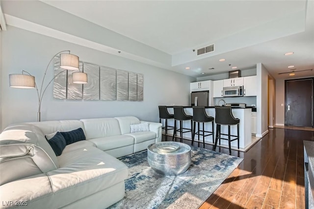 living area featuring visible vents, recessed lighting, and dark wood-type flooring