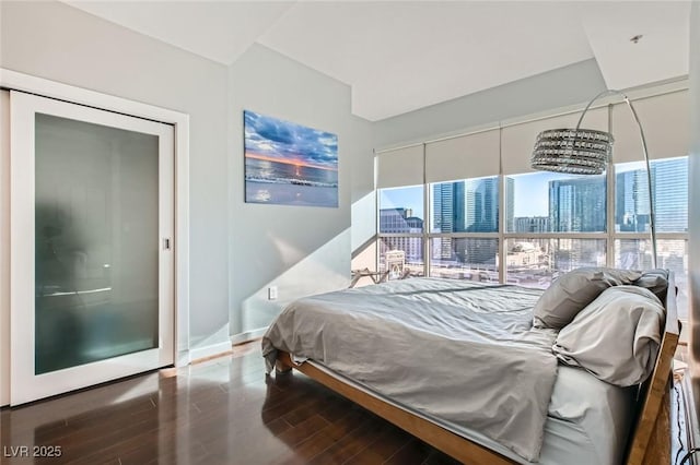 bedroom featuring baseboards, wood finished floors, and a view of city