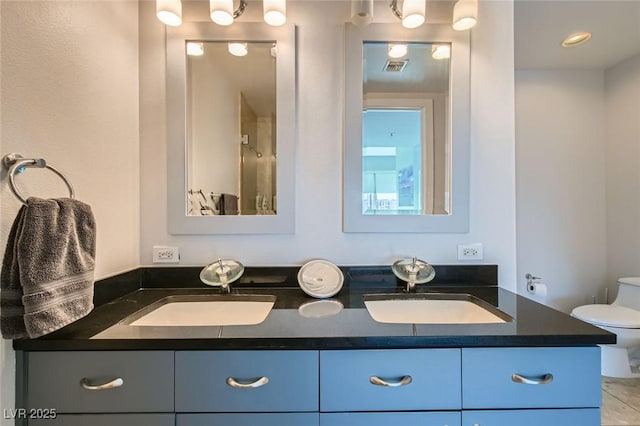 full bathroom with a sink, visible vents, toilet, and double vanity